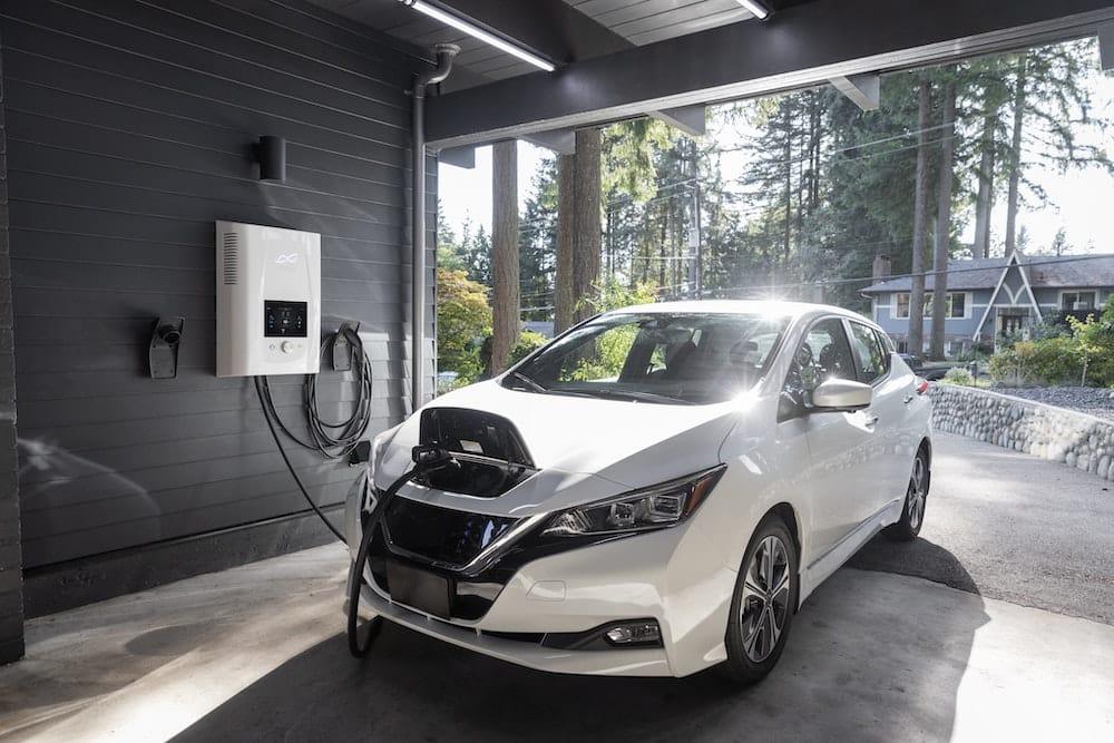 An electric vehicle plugged in and charging in a home's garage.