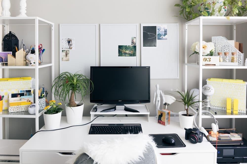 A computer on a desk surrounded by other electronics.